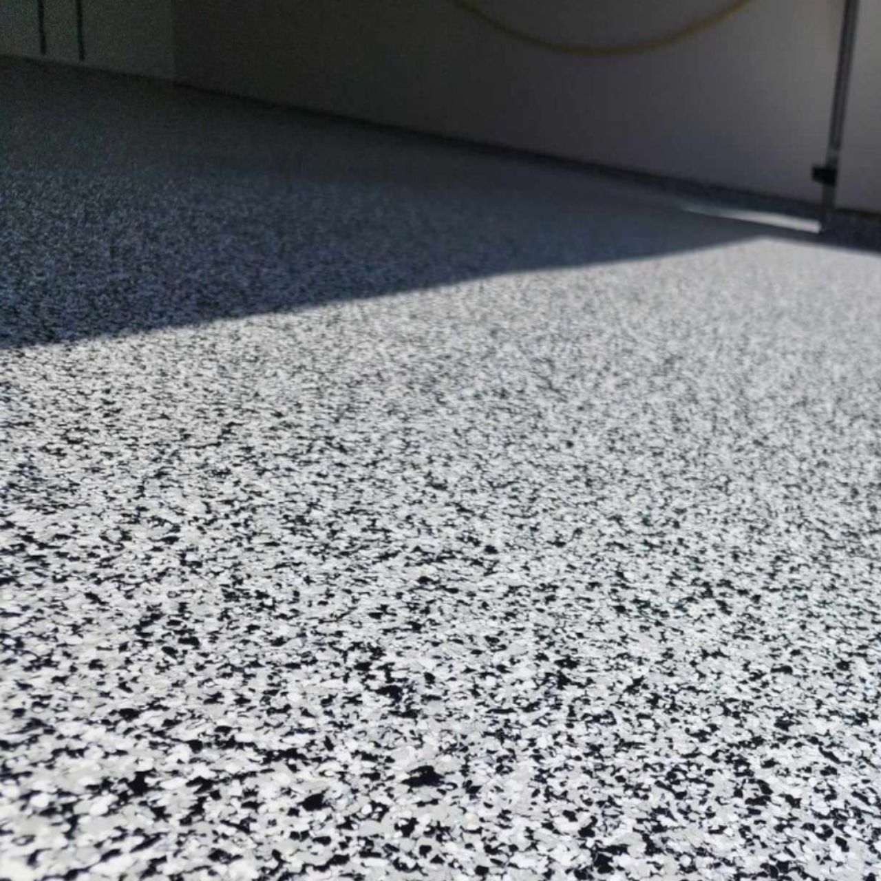 Closeup of black and white full-broadcast flake epoxy floor near Versailles Missouri