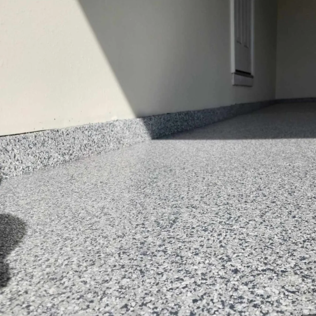 Cove base corner detail on a gray flake epoxy garage floor