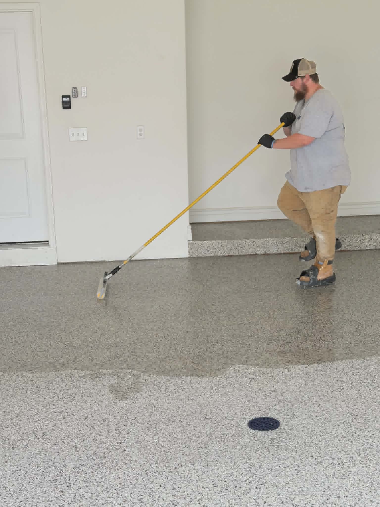 Show Me Epoxy installer applying topcoat with squeegee on garage floor Missouri