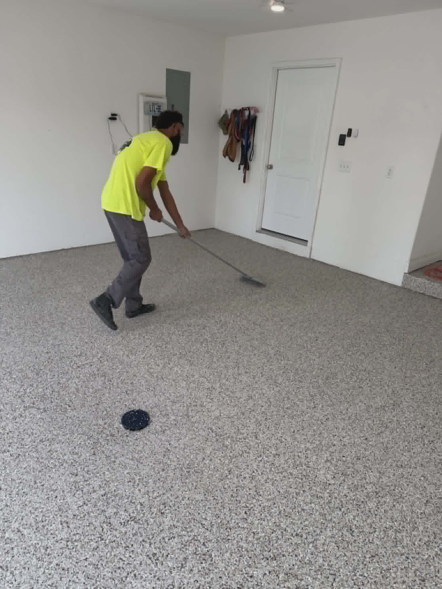 Show Me Epoxy installer applying topcoat with a squeegee on a garage floor